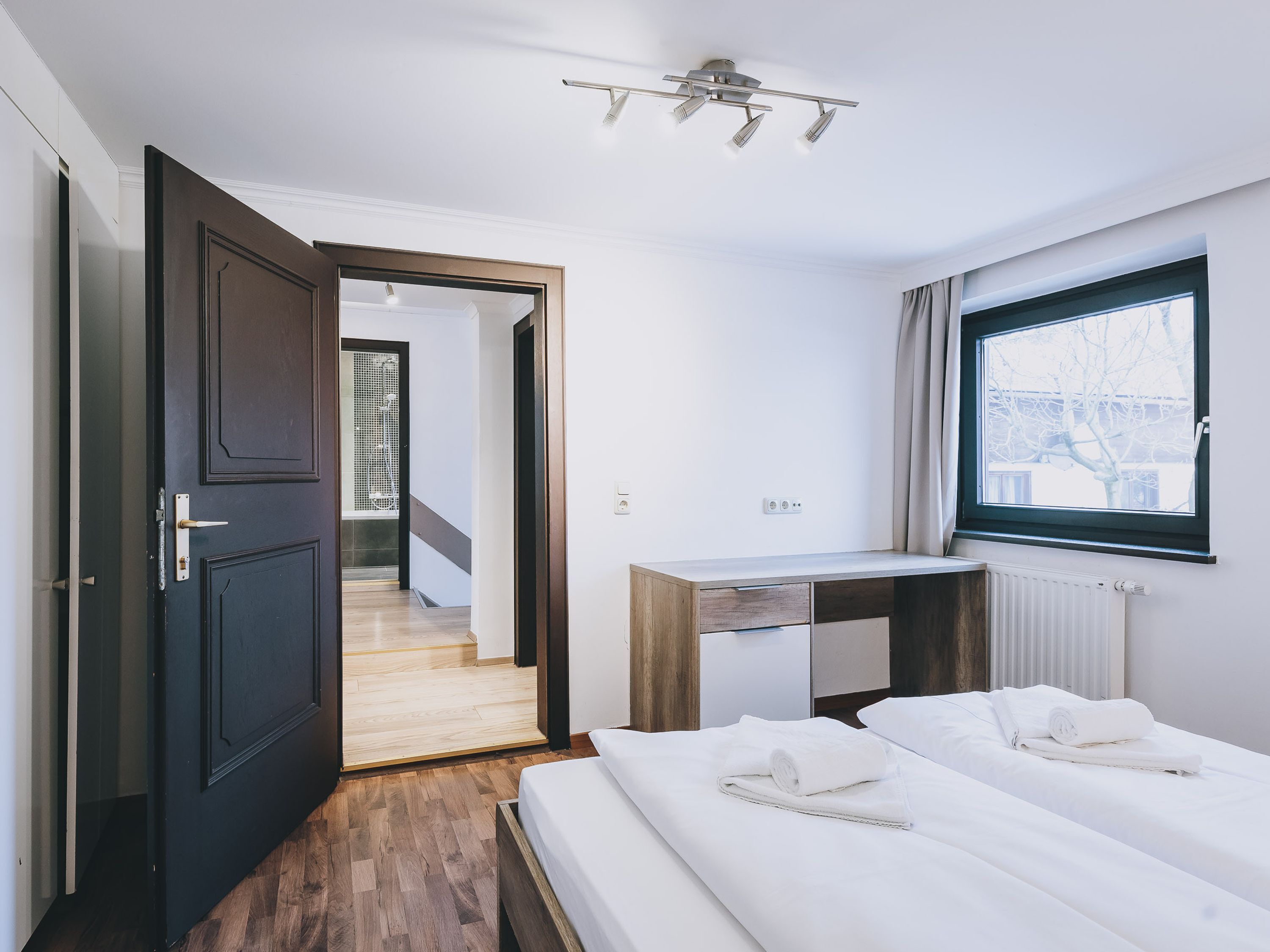 Ett modernt hotellrum med en säng, ett skrivbord och ett fönster.
