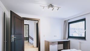 A modern hotel room with a bed, a desk, and a window. - Areit Apartments - Top 3 (Zell am See)