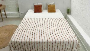 Un dormitorio pequeño y moderno con cama, dos almohadas, una mesita de noche y una ventana.