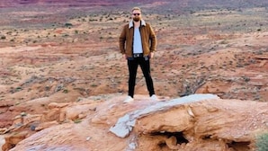 Una persona parada sobre un afloramiento rocoso, con un paisaje desértico y formaciones de roca al fondo.