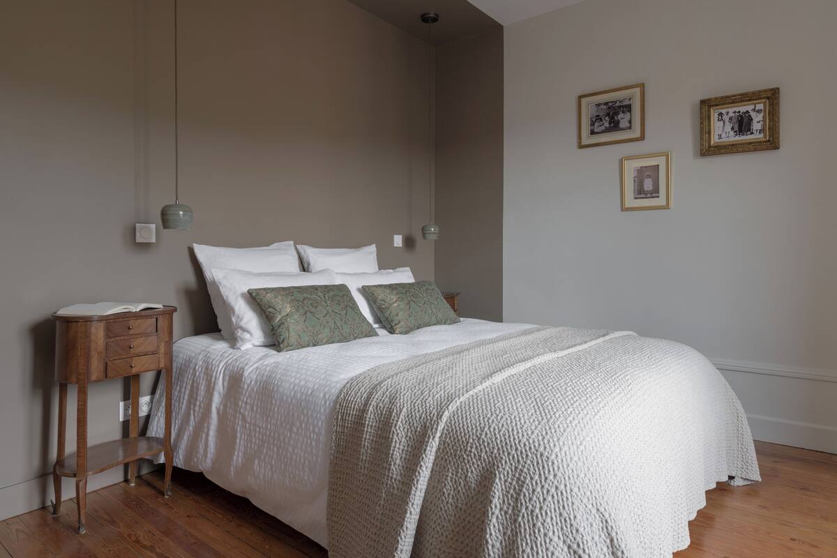 A bedroom with a bed, a bedside table, and a wall-mounted light fixture.