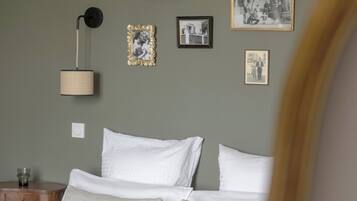 Un dormitorio con cama, mesita de noche, lámpara y cuadros en la pared.