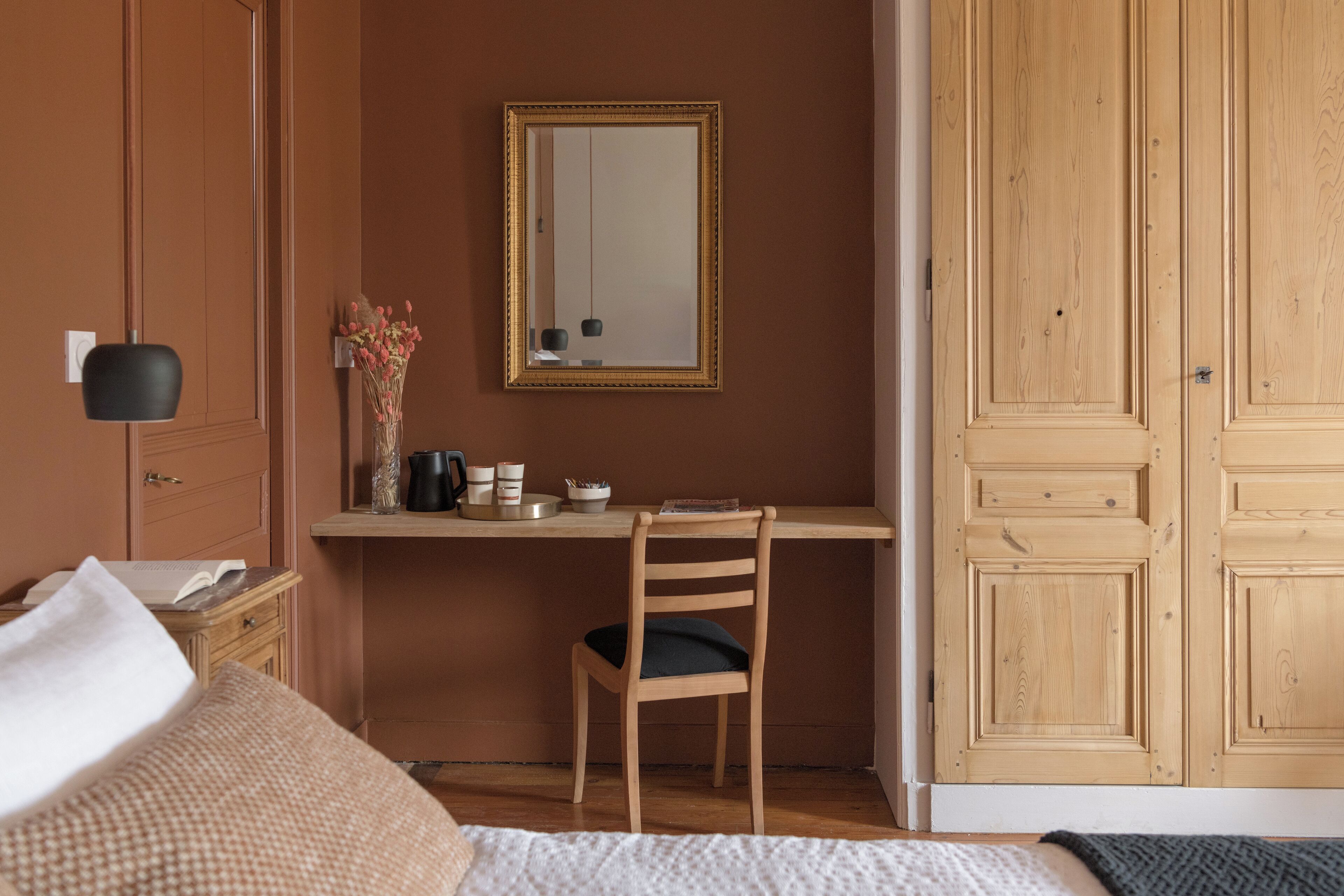 Un dormitorio con un escritorio de madera, una silla, una cama y un armario.