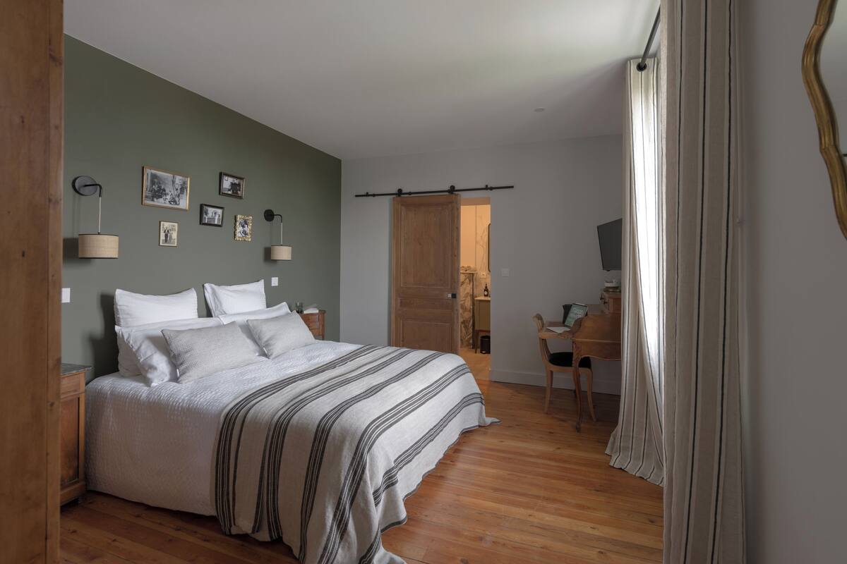 A bedroom with a bed, bedside tables, a desk, and a chair.
