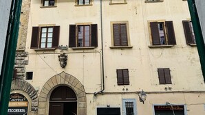 A building with a central entrance, multiple windows with shutters, and a sign for a pizzeria. - Prime Rooms Verdi (Florence)