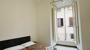 A bedroom with a bed, a ceiling light fixture, and a view of the outside balcony. - Prime Rooms Verdi (Florence)