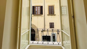 A narrow balcony with a view of a building with multiple windows and shutters. - Prime Rooms Verdi (Florence)