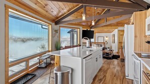 Una cocina amplia con vigas de madera, ventanas grandes y vistas a un paisaje nevado.