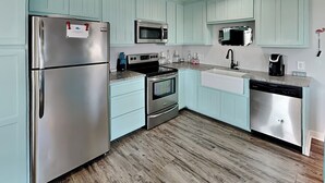 Una cocina moderna con armarios azul claro, electrodomésticos de acero inoxidable y piso de madera.