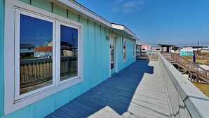 Un edificio costero con terraza de madera y ventanas amplias.