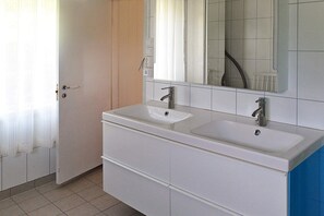 Ein Badezimmer mit zwei Waschbecken, einem Spiegel und einer Tür.