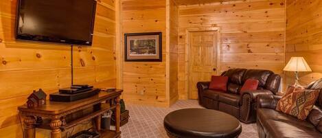 A log cabin interior with a wooden TV stand, leather sofa, and a framed picture on the wall.
