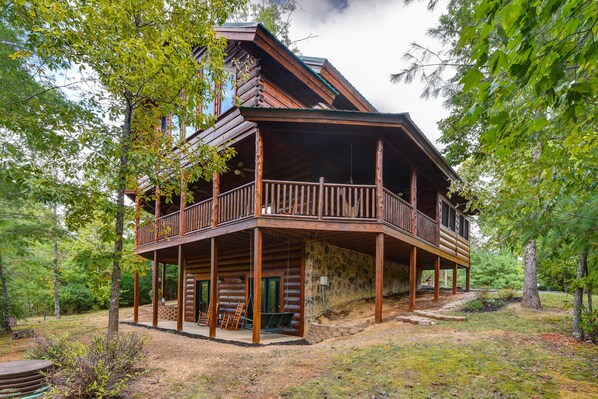 A log cabin with a balcony, surrounded by trees.