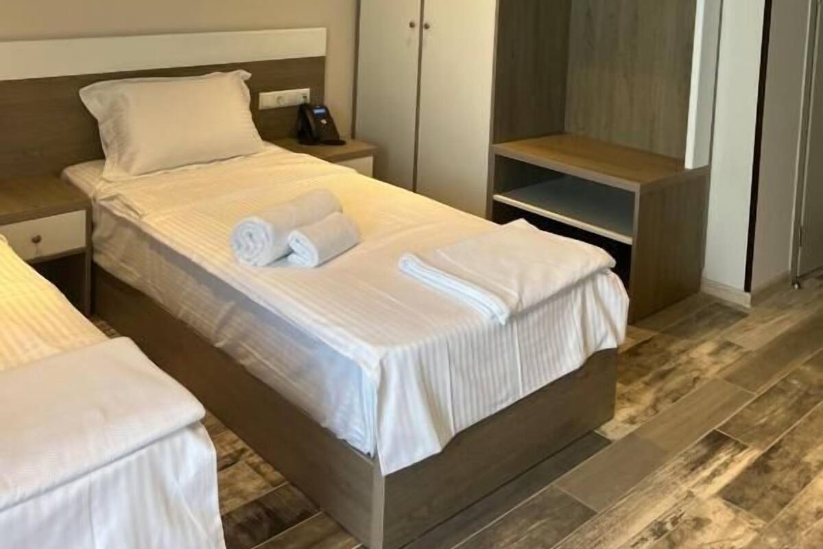 A hotel room with two beds, a wardrobe, and a small desk.