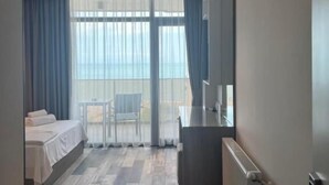 Ein Hotelzimmer mit Bett, Schreibtisch, Stuhl und einem großen Fenster mit Vorhängen.