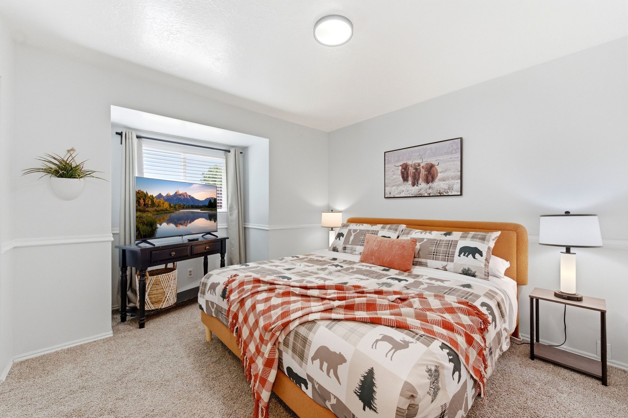 A bedroom with a bed, bedside lamps, a desk, a window with a view, and a wall-mounted plant.