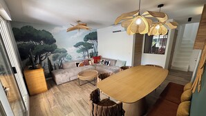 A modern living room with a wooden dining table, a sofa, and a ceiling fan. - Magnificent air-conditioned duplex, 3 bedrooms, 2 large terraces, swimming pool & beach on foot! (Le Lavandou)