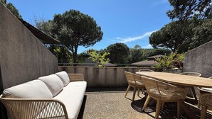 An outdoor patio with a sofa, wicker chairs, and a wooden table. - Magnificent air-conditioned duplex, 3 bedrooms, 2 large terraces, swimming pool & beach on foot! (Le Lavandou)