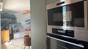 A modern kitchen with built-in appliances, a wooden floor, and a mural on the wall. - Magnificent air-conditioned duplex, 3 bedrooms, 2 large terraces, swimming pool & beach on foot! (Le Lavandou)