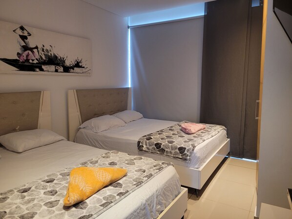 Une chambre d’hôtel avec deux lits, un tableau au mur et une fenêtre donnant sur un beau paysage.