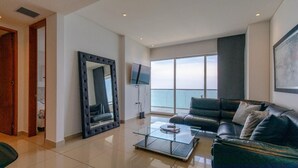 A modern living room with a glass coffee table, leather sofa, and a large mirror. -  H2 Bocagrande Vista al Mar-Bahía (Cartagena)