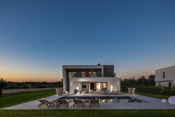 Una casa moderna de dos pisos con piscina y zona de estar al aire libre.