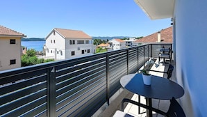 A balcony with a table and chairs, overlooking a body of water and buildings. - 2-Bedroom Holiday Apartment with Sea-view Balcony! (Orebic)