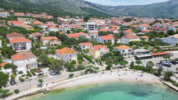 A coastal town with residential buildings, a beach, and mountains in the background. - 2-Bedroom Holiday Apartment with Sea-view Balcony! (Orebic)