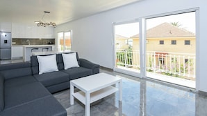 A modern living room with a grey sofa, white cushions, a white coffee table, and a kitchen in the background. - 2-Bedroom Holiday Apartment with Sea-view Balcony! (Orebic)