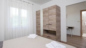 A hotel room with a bed, a wooden wardrobe, a desk, and a chair. - Great 2-Bedroom Holiday Apartment with terrace and sea-view! (Orebic)