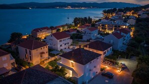 A coastal town at dusk with buildings along the waterfront, a marina, and a view of the sea. - Great 2-Bedroom Holiday Apartment with terrace and sea-view! (Orebic)