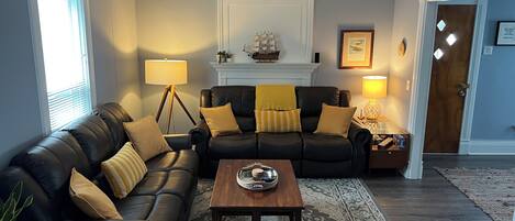 A living room with a black leather sofa, a wooden coffee table, and a patterned rug.