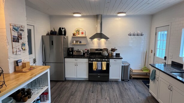 Een moderne keuken met witte bakstenen muren, houten vloeren, roestvrijstalen apparatuur en een centraal eiland.