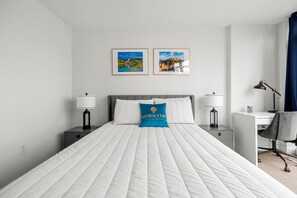 A hotel room with a large bed, two bedside tables with lamps, a desk with a chair, and two framed pictures on the wall. - GLOBALSTAY 1 Bedroom with a Romantic View of Trains in Downtown (Toronto/Canada)
