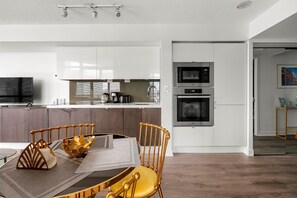 A modern kitchen with white cabinets, a dining area with a wooden table and chairs, and a built-in oven. - GLOBALSTAY 1 Bedroom with a Romantic View of Trains in Downtown (Toronto/Canada)