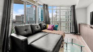 A modern living room with a leather sofa, a glass coffee table, and a view of tall buildings. - GLOBALSTAY 1 Bedroom with a Romantic View of Trains in Downtown (Toronto/Canada)