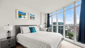 A modern hotel room with a large bed, two bedside tables, a desk, and a view of the city through large windows. - GLOBALSTAY 1 Bedroom with a Romantic View of Trains in Downtown (Toronto/Canada)
