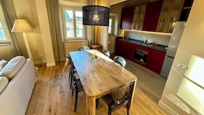 Una cocina moderna con armarios rojos, una mesa de comedor de madera y un horno empotrado.