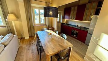 A modern kitchen with red cabinets, a wooden dining table, and a built-in oven.