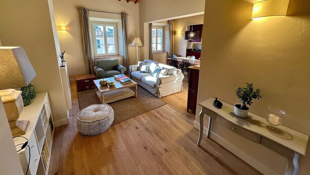 Una sala de estar acogedora con techo de madera, un sofá blanco, una mesita de centro y un comedor con lámpara.