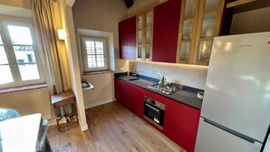Una cocina con gabinetes rojos, estufa a gas y refrigerador blanco.