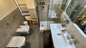 A modern bathroom with a glass shower enclosure, a toilet, a bidet, and a vanity with a mirror. - Villa 7 (Bagno A Ripoli)