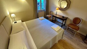 A hotel room with a bed, a desk, a chair, a lamp, and a window with curtains. - Villa 7 (Bagno A Ripoli)