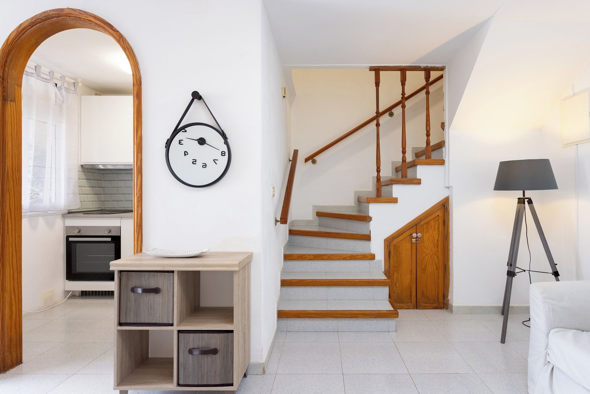 A modern kitchen with white cabinets, a wooden countertop, and a hanging clock.