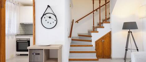 A modern kitchen with white cabinets, a wooden countertop, and a hanging clock.