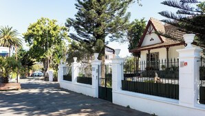 A gated entrance with a white building, a tiled roof, and a large tree in the background. - Home2Book Modern Apt Indoor Terrace, La Laguna (San Cristóbal de La Laguna)