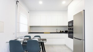 A modern kitchen with white cabinets, a stainless steel refrigerator, and a dining table with four chairs. - Home2Book Modern Apt Indoor Terrace, La Laguna (San Cristóbal de La Laguna)