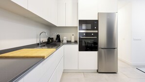 A modern kitchen with white cabinets, a stainless steel refrigerator, a microwave, and a coffee maker. - Home2Book Modern Apt Indoor Terrace, La Laguna (San Cristóbal de La Laguna)