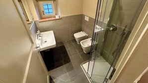 A compact bathroom with a glass-enclosed shower, a sink, and a toilet. - Villa 16 (Bagno A Ripoli)