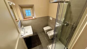 Un bagno compatto con cabina doccia in vetro, lavandino e WC.